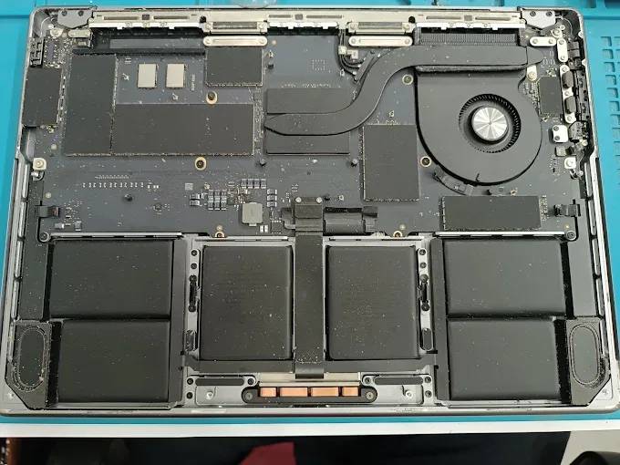 MacBook opened up on the bench at FixBox Ubud, logic board and battery cells exposed